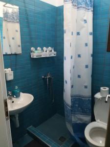 a blue tiled bathroom with a toilet and a sink at Vasileiou in Kala Nera