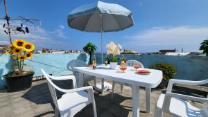 een witte tafel en stoelen met een parasol op een balkon bij Stella Marina in Genua