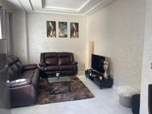 uma sala de estar com um sofá de couro e uma televisão em Appartement Casablanca Maarif em Casablanca