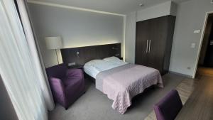 a bedroom with a bed and a purple chair at Nice Apartment in modern Center of Düsseldorf in Düsseldorf