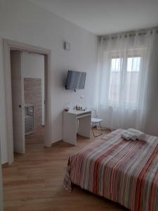 a white bedroom with a bed and a desk and window at Aer Sana in Arzana