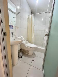 y baño con lavabo, aseo y ducha. en Suite Hotel Olimpico, en Huancayo