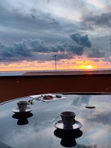 a reflection of two cups on a table with a sunset at Przytulny apartament w Belvedere Marittimo in Belvedere Marittimo