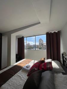 a dog laying on a bed in a bedroom with a window at Suite Hotel Olimpico in Huancayo