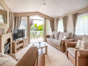 a living room with a couch and a tv at Tradmach Lodge in Patrington