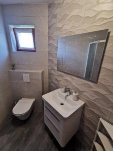 a bathroom with a white sink and a toilet at Apartments Nice View in Krk