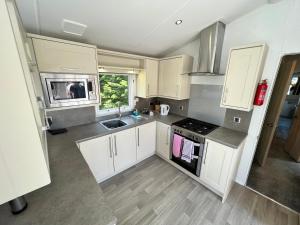 3 Bedroom Caravan LG34, Lower Hyde, Shanklin في شانكلين: مطبخ بدولاب بيضاء وفرن علوي موقد