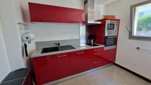 cocina roja con fregadero y nevera en Appartement T3 de 74m2 très lumineux vue panoramique mer et plages en Concarneau