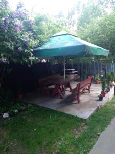 einen Picknicktisch mit einem blauen Regenschirm auf einer Terrasse in der Unterkunft Vila Bogdan in Buşteni