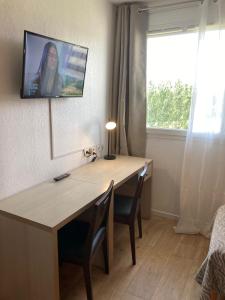 Cette chambre dispose d'une table avec des chaises et d'une télévision murale. dans l'établissement Appart'Hotel - Gare TGV - Courtine - Confluence - 407, à Avignon