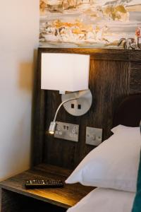 a lamp on a side table next to a bed at The Bull Hotel in Stony Stratford