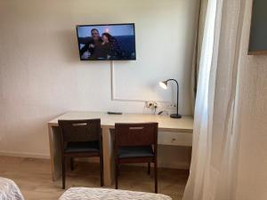 Pokój z biurkiem z 2 krzesłami i telewizorem na ścianie w obiekcie Appart'Hotel - Gare TGV - Courtine - Confluence - 407 w Awinionie