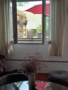 a window with an umbrella and a table with a vase at Apartman T and T in Ražanac