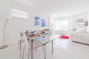 a white living room with a glass table and chairs at 2 BEDROOM ON THE BEACH ! in Miami Beach