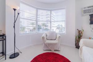 a white living room with a chair and a red rug at 2 BEDROOM ON THE BEACH ! in Miami Beach