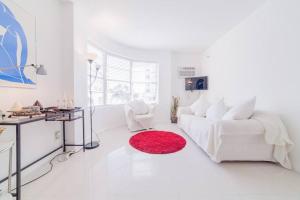 a white living room with a white couch and a red rug at 2 BEDROOM ON THE BEACH ! in Miami Beach