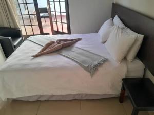 a bed with a blanket and pillows on it at Ethithiya Boutique Guesthouse in Windhoek