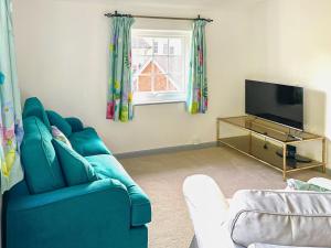 un soggiorno con divano blu e TV di Garden Cottage 2 - Uk42882 a Liphook