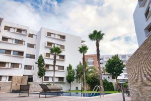 ein Apartmentgebäude mit einem Pool und Palmen in der Unterkunft Luxury Apartment 90sqm with Pool near Beach WIFI Unlimited Optical Fiber in Agadir