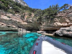 a boat in a river next to a rocky cliff at Turismo Rurale Belvedere Pradonos in Dorgali