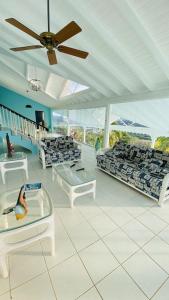 sala de estar con sofás y ventilador de techo. en Villa Ocean Blu, en Cap Estate