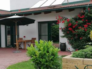 a patio with an umbrella and a table and flowers at Gästehaus Samira in Purbach am Neusiedlersee