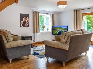 a living room with two chairs and a tv at Bryn Bannon in Cilcain
