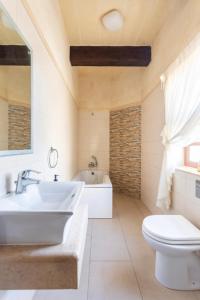 a bathroom with a sink and a toilet and a tub at Inzolia - Peaceful Villa with Pool in Il-Pergla