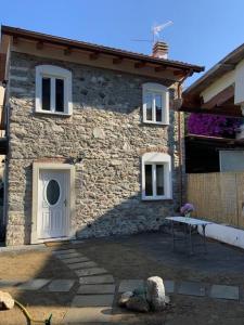 une maison en pierre avec une porte blanche et une table à l'extérieur dans l'établissement Casa in pietra in antico borgo vicino al centro, à Pietrasanta