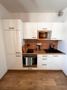 Apartmán Kašperák في كاسبيرسكي هوري: مطبخ أبيض مع حوض وميكروويف