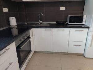 a kitchen with white cabinets and a sink and a microwave at Orange Tree House in Šipanska Luka