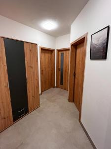 an empty room with wooden doors and a hallway at Apartmán Kašperák in Kašperské Hory