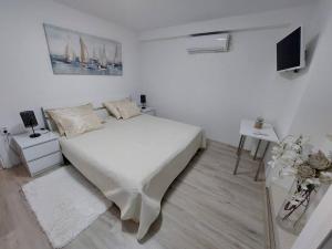 a white bedroom with a bed and a tv at Orange Tree House in Šipanska Luka