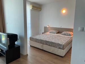 sypialnia z łóżkiem i telewizorem w obiekcie апартамент в Сарафово w Burgas