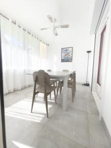 a white dining room with a table and chairs at L'Hermitage - Appartement T3 en bord de plage in Filaos