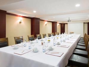 Premier Inn Express Gulberg Lahore في لاهور: قاعة اجتماعات مع طاولة طويلة مع طاولات بيضاء وكراسي