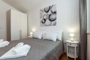 a white bedroom with a bed with towels on it at Apartman Enzzo in Šibenik