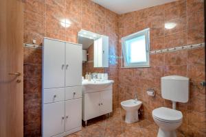 a bathroom with a toilet and a sink and a mirror at Apartman Enzzo in Šibenik +20 photos