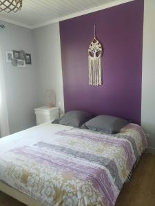 a bedroom with a bed with a purple wall at Chambre Zen à la campagne in Marennes