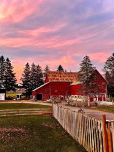 a red barn with a fence in front of it at The Barns of Brighton Near Prince Edward County in Brighton