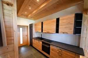 a kitchen with wooden cabinets and a black stove at Holzwies Chalets in Unterneukirchen