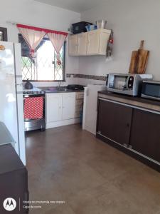 een keuken met witte kasten en een magnetron bij Casa de Praia em Barra Velha Itajuba SC por Temporada in Barra Velha