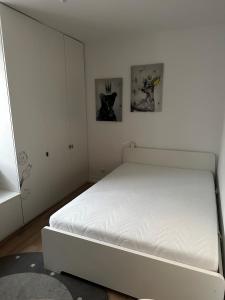 białe łóżko w sypialni z dwoma zdjęciami na ścianie w obiekcie Duże mieszkanie blisko plaży w Gdańsku