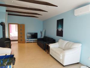 a living room with a white couch and a tv at Spacious 110 M2 Apartment With Forest View in Zapyškis