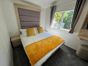 a bedroom with a bed with yellow pillows and a window at 3 Bedroom Caravan LG34, Lower Hyde, Shanklin in Shanklin
