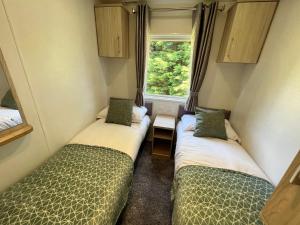 two beds in a small room with a window at 3 Bedroom Caravan LG34, Lower Hyde, Shanklin in Shanklin +9 photos