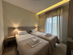 a hotel room with two beds and a window at Yulia Luxury Apartment in Ouranoupoli