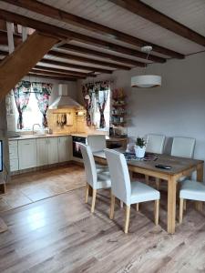 a kitchen with a wooden table and white chairs at Wczasy u Reni in Kopalino