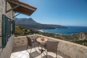 una mesa y sillas en un balcón con vistas al océano en Olga's House en Neo Oitilo