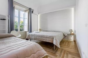 ein weißes Schlafzimmer mit 2 Betten und einem Fenster in der Unterkunft Calypso Il Binario Elegance in Palermo